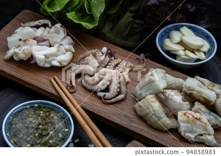 Fresh grilled squid, Octopus tentacles and Squids eggs on Wooden tray Served with Fresh vegetables and Spicy seafood dipping sauce.  94838983