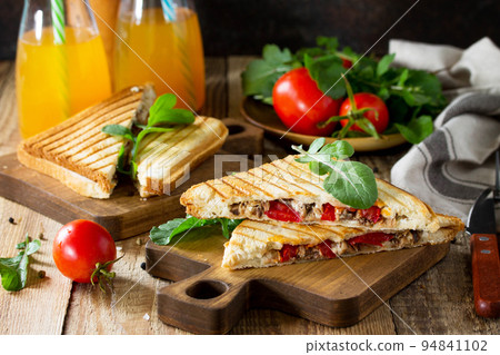 Concept of breakfast. Fruit Juice and delicious fresh Homemade Sandwich with tuna fish, tomatoes, cheese on a wooden kitchen table. Concept of breakfast. Fruit Juice and delicious fresh Homemade Sandwich with tuna fish, tomatoes, cheese on a wooden kitchen table. 94841102