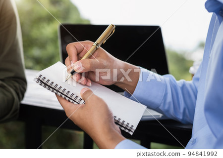 Male hands taking notes on a handwritten notepad, creative writing. Male hands taking notes on a handwritten notepad, creative writing. 94841992