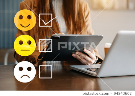 Customer service evaluation concept. woman Show face smile emoticon show on virtual screen from hand.looking at smart phone, tablet and laptop Customer service evaluation concept. woman Show face smile emoticon show on virtual screen from hand.looking at smart phone, tablet and laptop 94843602