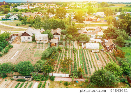 Close-up Aerial View On Houses Of Small Village. Houses And Vegetable Gardens. Home Plantations At Summer Day. Village Gardens. Household Plots Close-up Aerial View On Houses Of Small Village. Houses And Vegetable Gardens. Home Plantations At Summer Day. Village Gardens. Household Plots 94845681