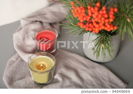 rowanberry and pine branch in a concrete vase and glowing candles on grey background. blog autumn content. rowanberry and pine branch in a concrete vase and glowing candles on grey background. blog autumn content. 94848669