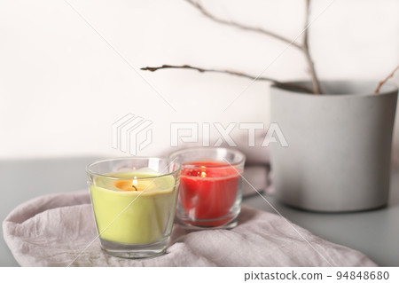 glowing candles on linen textile next to cement vase with tree branch. aesthetic composition home decor and cozy ambience 94848680