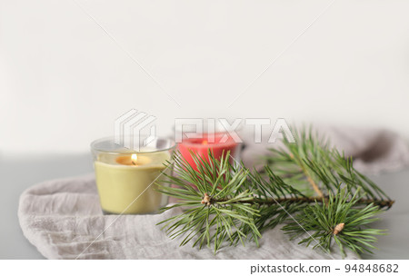winter holiday or weekend ambient still life. glowing soy wax candles in glass pots and pine tree needles on soft textile tablecloth. cozy home, calm and peaceful decor for fall season winter holiday or weekend ambient still life. glowing soy wax candles in glass pots and pine tree needles on soft textile tablecloth. cozy home, calm and peaceful decor for fall season 94848682