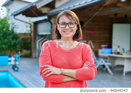 Portrait of smiling middle aged woman looking at camera outdoor 94849747