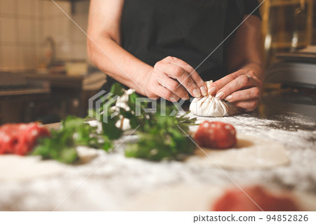 Chef of a Georgian restaurant sculpts khinkali. Khinkali cooking process. Chef of a Georgian restaurant sculpts khinkali. Khinkali cooking process. 94852826