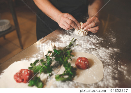 Chef of a Georgian restaurant sculpts khinkali. Khinkali cooking process.. Chef of a Georgian restaurant sculpts khinkali. Khinkali cooking process.. 94852827