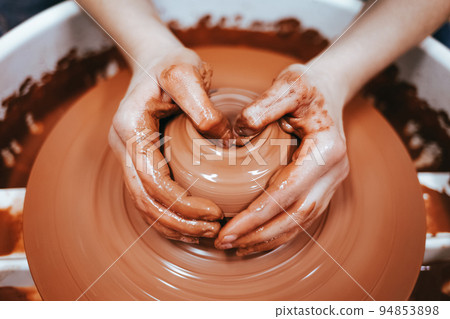 Potter forms clay products into future ceramic dishes. Process of creating clay products close-up Potter forms clay products into future ceramic dishes. Process of creating clay products close-up 94853898