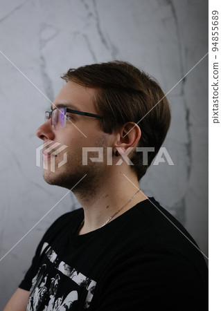 Unshorn and unshaven guy in glasses and black tshirt with long hair on gray background 94855689