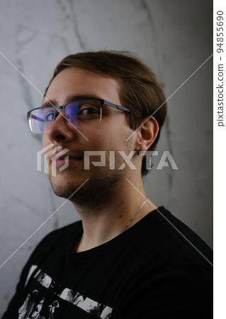 Unshorn and unshaven guy in glasses and black tshirt with long hair on gray background 94855690