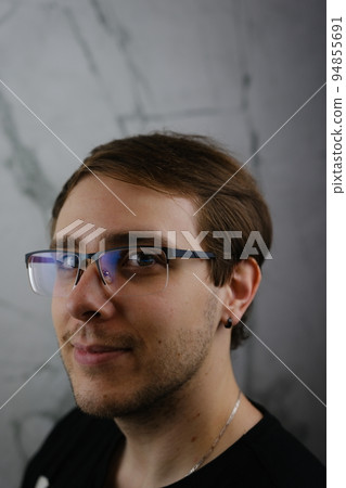 Unshorn and unshaven guy in glasses and black tshirt with long hair on gray background 94855691
