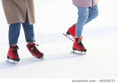 Feet of people skating on a street ice rink 94856513