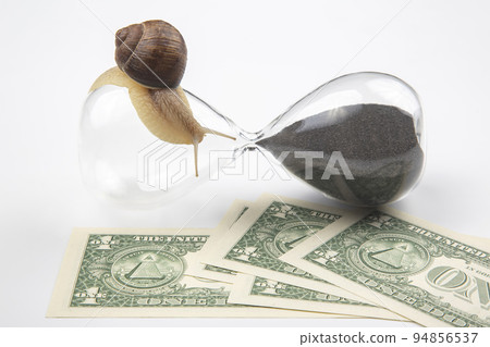 snail crawls on an hourglass against the background of money snail crawls on an hourglass against the background of money 94856537