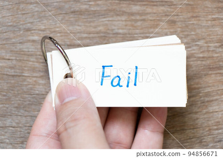 Hand hold flash card with handwriting in word fail on wood background 94856671