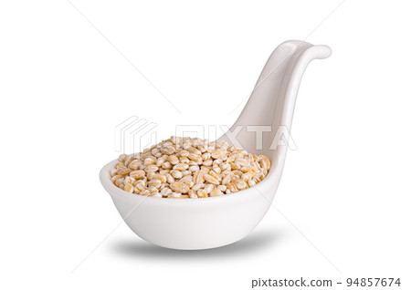 View of dried pearled barley seeds in white ceramic sauce cup. 94857674