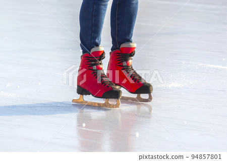 feet in red skates on an ice rink. hobbies and leisure. winter sports feet in red skates on an ice rink. hobbies and leisure. winter sports 94857801