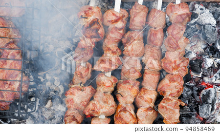 Delicious grilled pork meat in BBQ Barbecue with pork meat. Kebabs on the grill. Close-Up Of Meat On Barbecue Grill With Smoke. Delicious grilled pork meat in BBQ Barbecue with pork meat. Kebabs on the grill. Close-Up Of Meat On Barbecue Grill With Smoke. 94858469