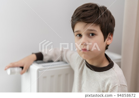 Baby boy playing with thermostat of heater stock photo