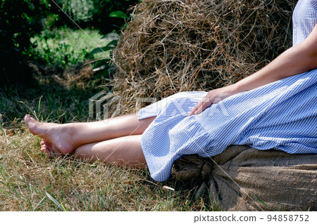 A barefoot girl in a blue cotton dress sits on... - Stock Photo ...