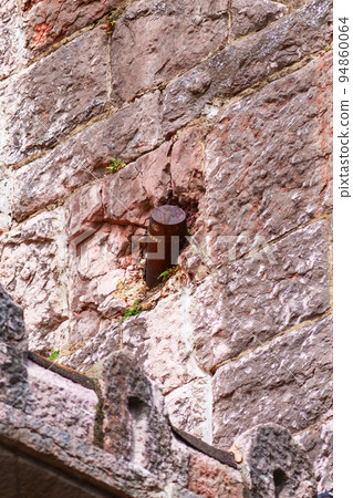 Old artillery shell in the destroyed wall of the building. Rusty projectile 94860064