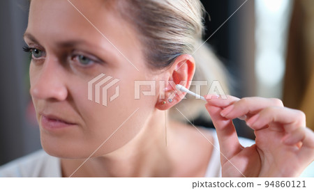 Woman cleans ears with cotton swabs closeup Woman cleans ears with cotton swabs closeup 94860121