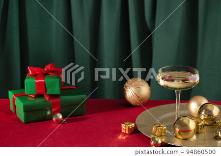 Merry Christmas and Happy New Year. Glass of champagne with golden Christmas ornaments and Christmas presents. 94860500