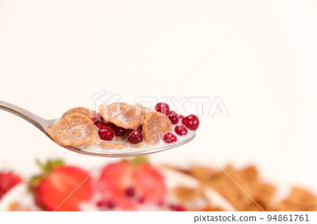 Cereal wheat flakes in milk with lingonberries in a spoon on a white background, a place for text. Quick healthy breakfasts Cereal wheat flakes in milk with lingonberries in a spoon on a white background, a place for text. Quick healthy breakfasts 94861761