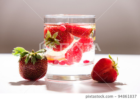 Summer cocktail with strawberries, raspberries and ice on a white background, side view. 94861837