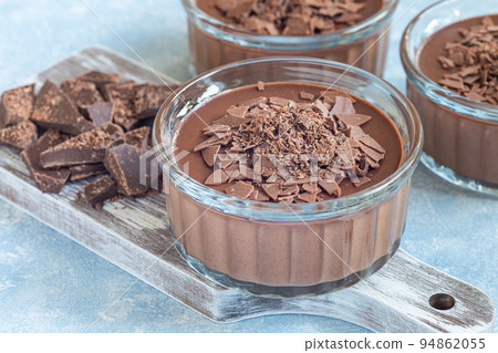 Chocolate Panna Cotta dessert in glass ramekin, wooden board and chocolate on background horizontal 94862055