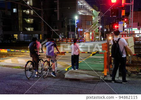 On the way home after sunset. People waiting for a train to pass at a railroad crossing 94862115