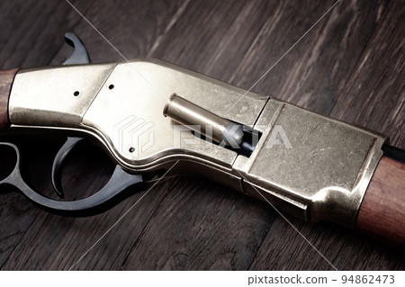 Old west lever-action repeating rifle with cartridge 94862473