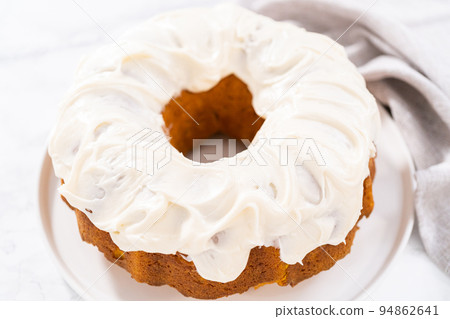 Freshly baked pumpkin bunt cake with cream cheese frosting on the kitchen counter. Freshly baked pumpkin bunt cake with cream cheese frosting on the kitchen counter. 94862641