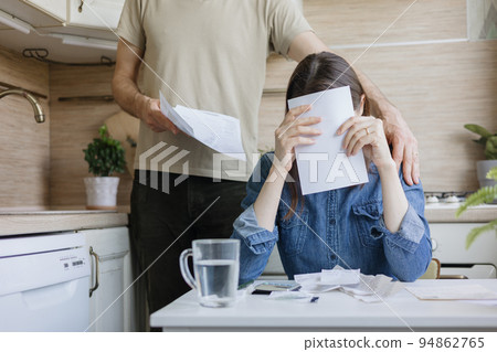 married couple, a man and a woman, are paying bills and utilities, a sad woman is experiencing financial difficulties married couple, a man and a woman, are paying bills and utilities, a sad woman is experiencing financial difficulties 94862765