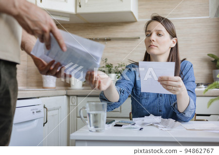 married couple, a man and a woman, are paying bills and utilities, a sad woman is experiencing financial difficulties married couple, a man and a woman, are paying bills and utilities, a sad woman is experiencing financial difficulties 94862767