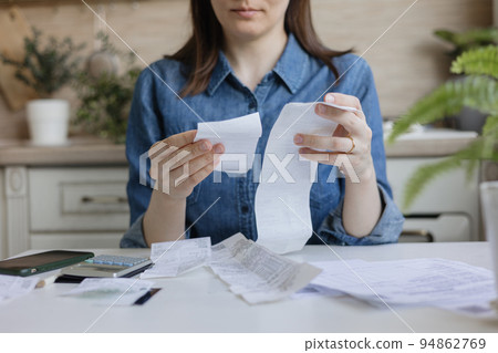 woman pays bills and utilities, counts the amount of expenses and income on a calculator woman pays bills and utilities, counts the amount of expenses and income on a calculator 94862769
