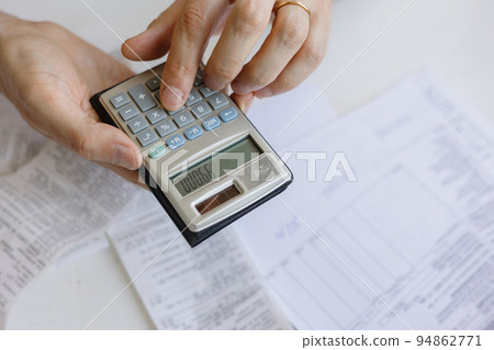 man pays bills and utilities, counts the amount of expenses and income on the calculator. Financial literacy and mortgage or rental payment man pays bills and utilities, counts the amount of expenses and income on the calculator. Financial literacy and mortgage or rental payment 94862771