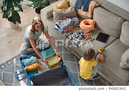 Mother and child are packing things in a suitcase together. Family relocation, flight from the country, closed borders Mother and child are packing things in a suitcase together. Family relocation, flight from the country, closed borders 94862942
