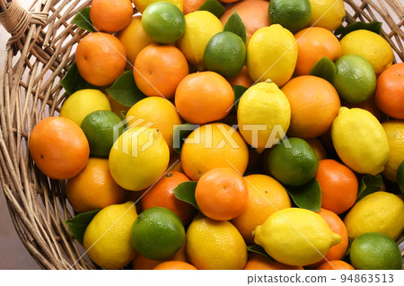 Colorful bright background of fresh ripe sweet citrus fruits in basket: orange and tangerine, green lime and yellow lemon Colorful bright background of fresh ripe sweet citrus fruits in basket: orange and tangerine, green lime and yellow lemon 94863513