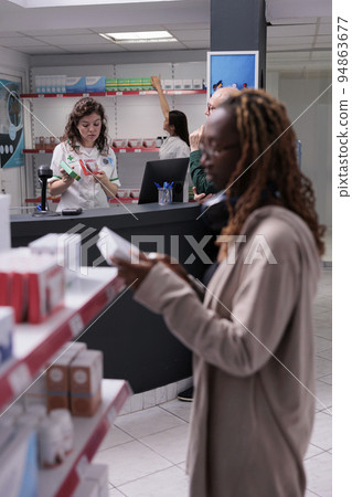 Pharmacy customers doing pharmaceutical shopping, buying vitamin, supplements for immune system. Elderly client discussing with drugstore worker asking for help with drugs prescription, 94863677