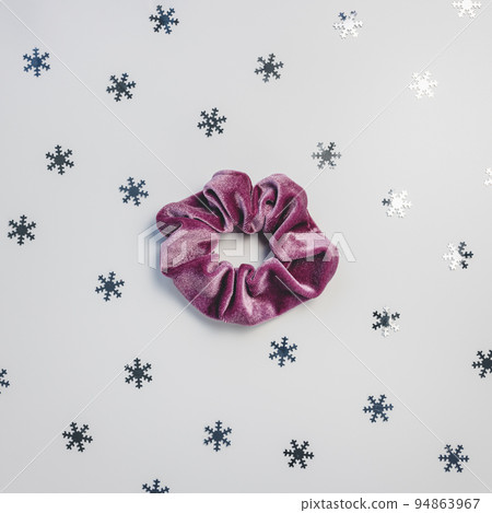 One purple velvet scrunchy and silver snowflakes on gray background. Winter trends and hairstyles concept One purple velvet scrunchy and silver snowflakes on gray background. Winter trends and hairstyles concept 94863967