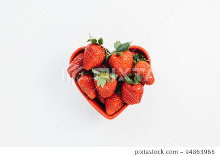 Fresh-picked strawberries in heart-shaped bowl on white background, concept of healthy eating vegan food. Summer snack. Closeup, selective focus, copy space Fresh-picked strawberries in heart-shaped bowl on white background, concept of healthy eating vegan food. Summer snack. Closeup, selective focus, copy space 94863968