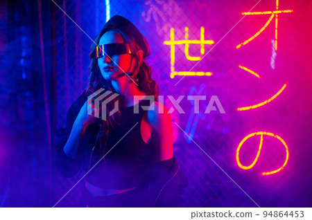 Caucasian woman in sunglasses posing in fog in neon studio. Caucasian woman in sunglasses posing in fog in neon studio. 94864453