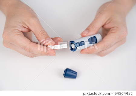 Caucasian woman inserts a needle into a lancet pen. Caucasian woman inserts a needle into a lancet pen. 94864455