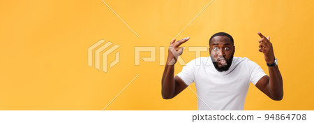 Portrait of african american man with hands raised in shock and disbelief. Isolated over yellow background. Portrait of african american man with hands raised in shock and disbelief. Isolated over yellow background. 94864708