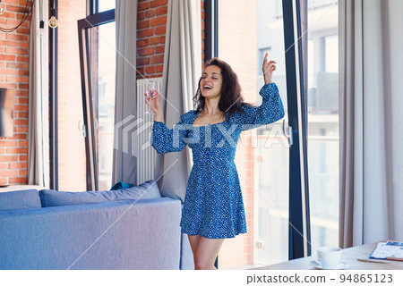 Lonely adorable dancing woman with glass of wine at cozy living room. Lonely adorable dancing woman with glass of wine at cozy living room. 94865123