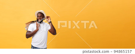 Happy african american man holding shopping bags on yellow background. Holidays concept Happy african american man holding shopping bags on yellow background. Holidays concept 94865157