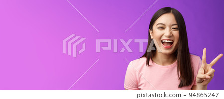 Headshot sincere carefree laughing asian girl having fun, show peace victory sign, joyfully look camera, express enthusiasm and happiness, enjoy funny friendly company, stand purple background 94865247