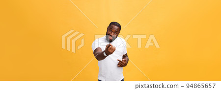 Funny young African customer smiling happily and pointing his index fingers at camera as if choosing you and inviting to big sale. Positive emotions, facial expressions, feelings. Selective focus. 94865657