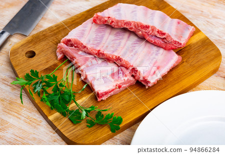 Uncooked pork ribs rack ready for cooking on cutting board 94866284