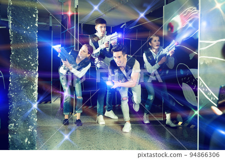 Modern young people with laser pistols playing laser tag on dark 94866306